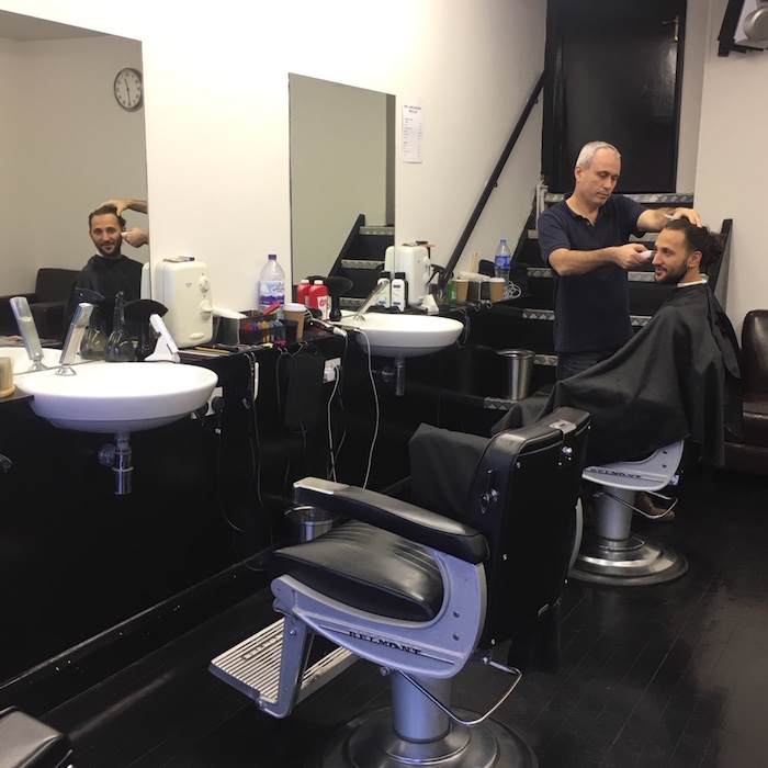 Barber cutting a customer's hair inside Mill Lane Barbers in 2017